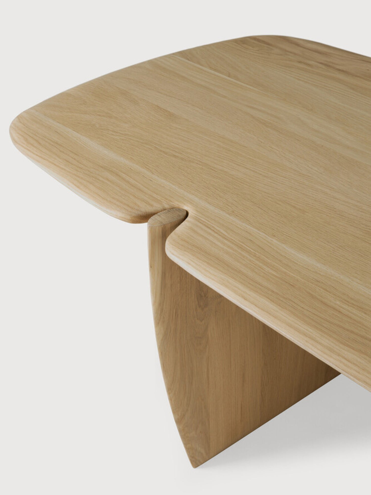 Ethnicraft PI Coffee Table in natural oak, rectangular shape. A close-up detail shot reveals the smooth, light wood grain and the seamless, elegant joint where the tabletop meets the leg, displayed on a white background.