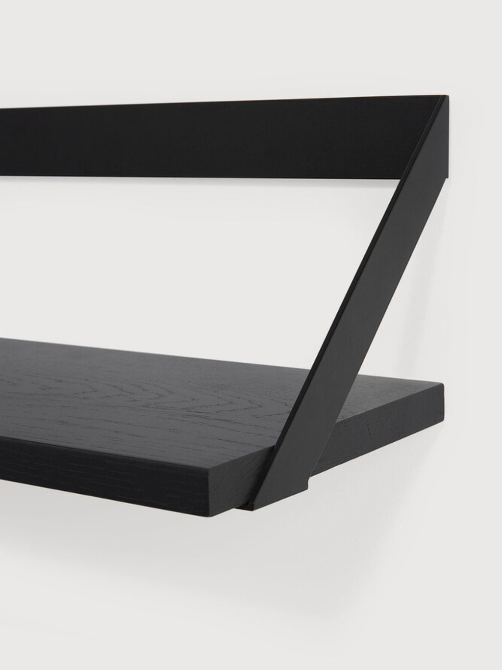 Ethnicraft Ribbon Shelf, a sleek modern minimalist wall shelf crafted from matte black solid oak with a visible wood grain, featuring a unique geometric matte black metal support bracket that creates a striking ribbon-like design. This contemporary floating shelf is perfect for stylish display or storage in living rooms, home offices, or bedrooms.