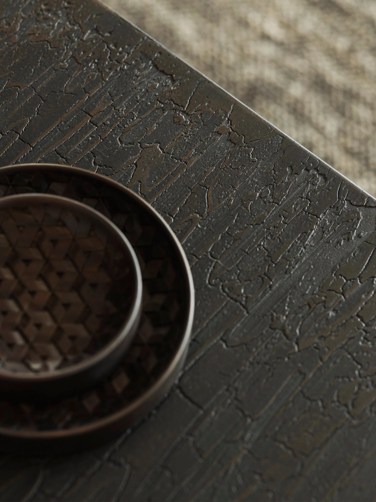 Ethnicraft Stability Coffee Table umber detail shot, highlighting the unique, deeply textured cracked surface of the dark brown tabletop, with a decorative woven bowl partially visible on the left.