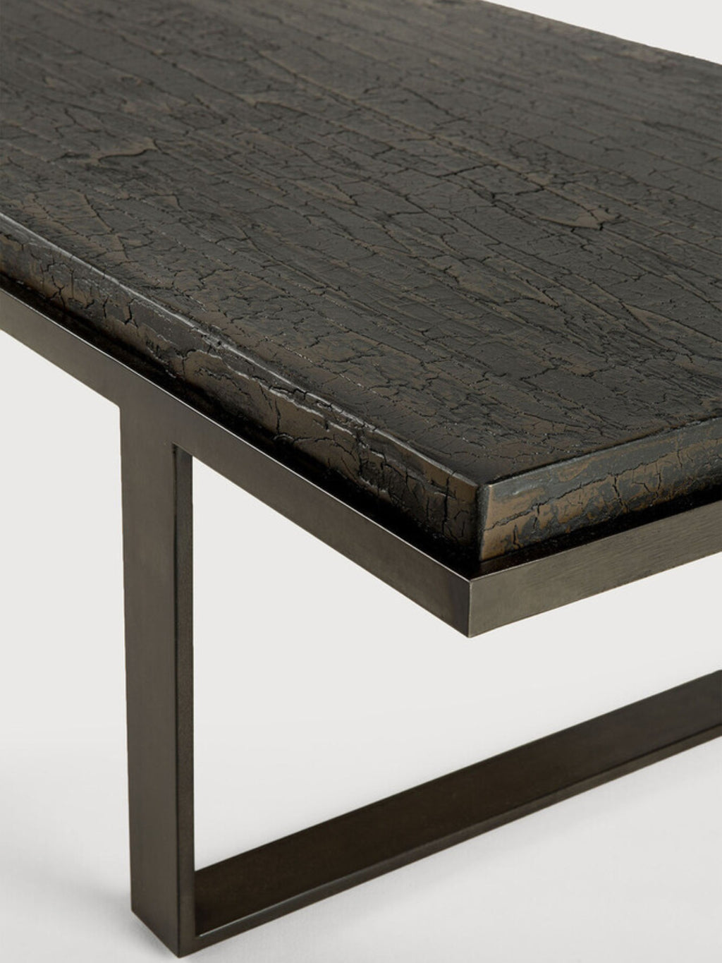 Ethnicraft Stability Coffee Table umber detail, showcasing the elegant rectangular tabletop with its distinctive dark, textured cracked finish, resting on a sturdy, minimalist black metal frame, viewed from an angle.