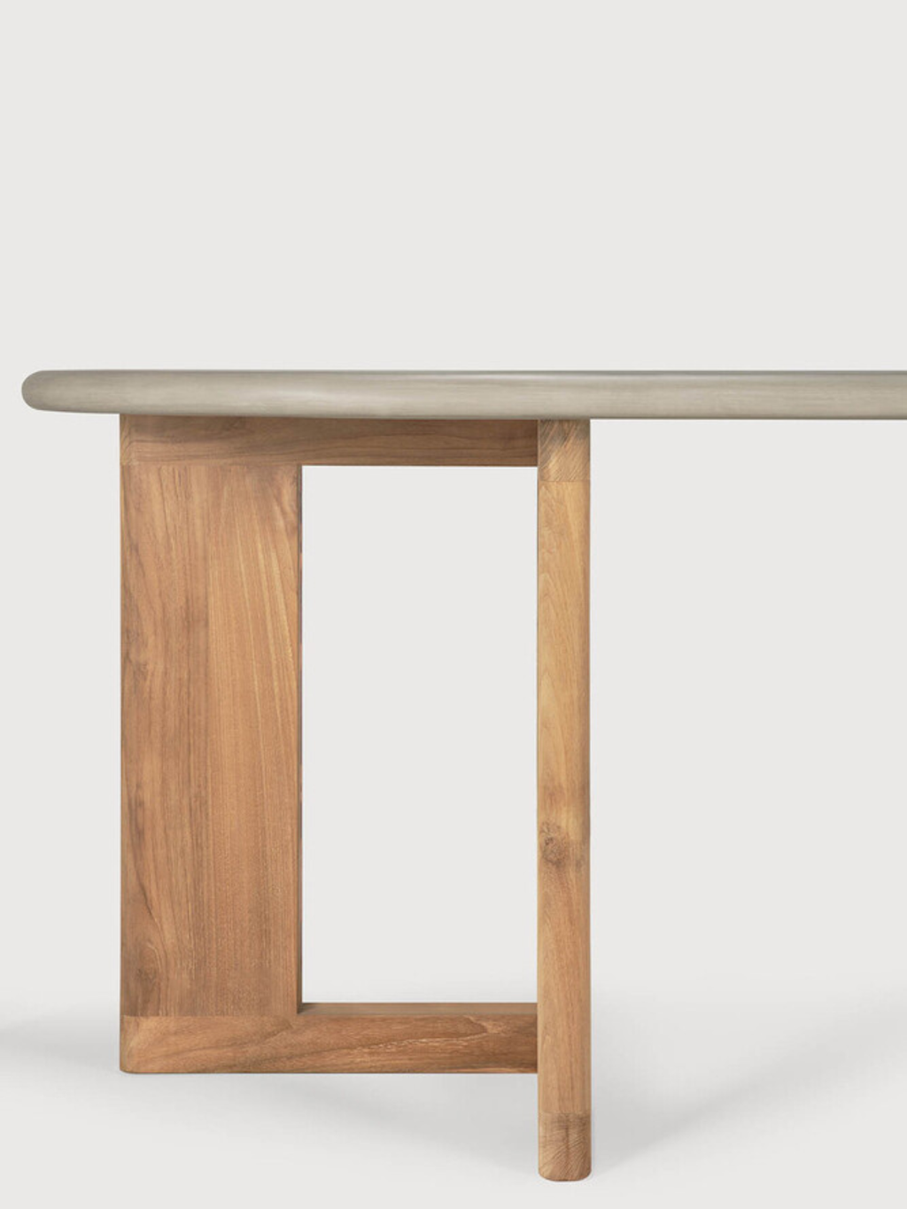 Ethnicraft Trestle Outdoor Dining Table, a modern minimalist outdoor table featuring a smooth, light grey concrete-look tabletop with softly rounded edges, supported by a natural teak wood trestle base with an architectural, open rectangular design. This contemporary wood and concrete patio table is perfect for stylish outdoor entertaining and modern garden spaces.