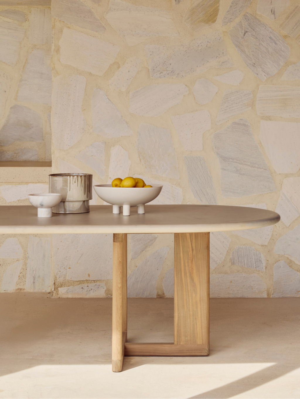 Ethnicraft Trestle Outdoor Dining Table, a modern minimalist oval dining table designed for outdoor living, featuring a smooth greige ceramic tabletop with subtle stone-like texture.