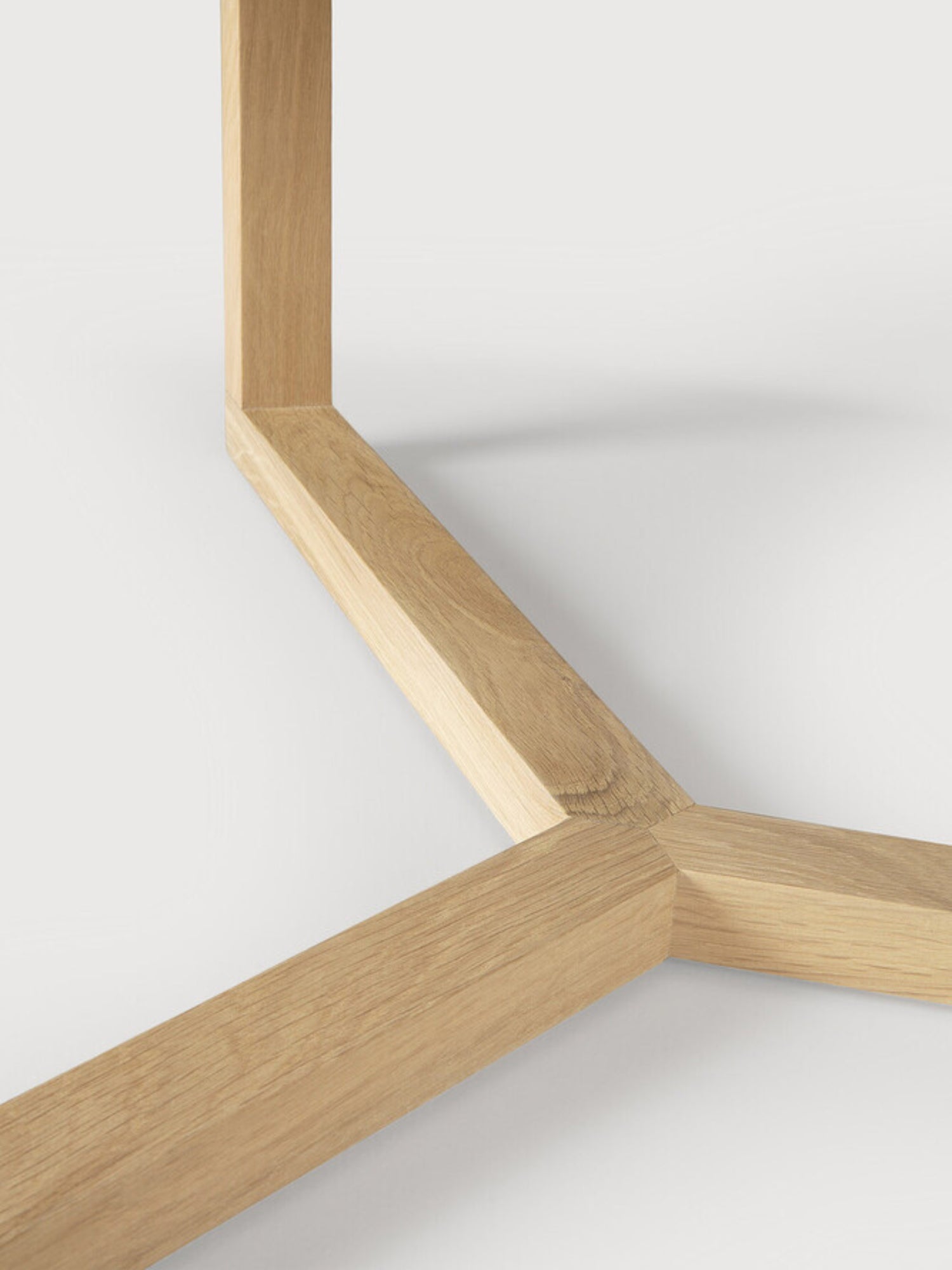 Ethnicraft Tripod Coffee Table, a close-up of the sturdy, light oak wood base, featuring the intricate joinery and geometric design of the three-legged support structure on a white background.