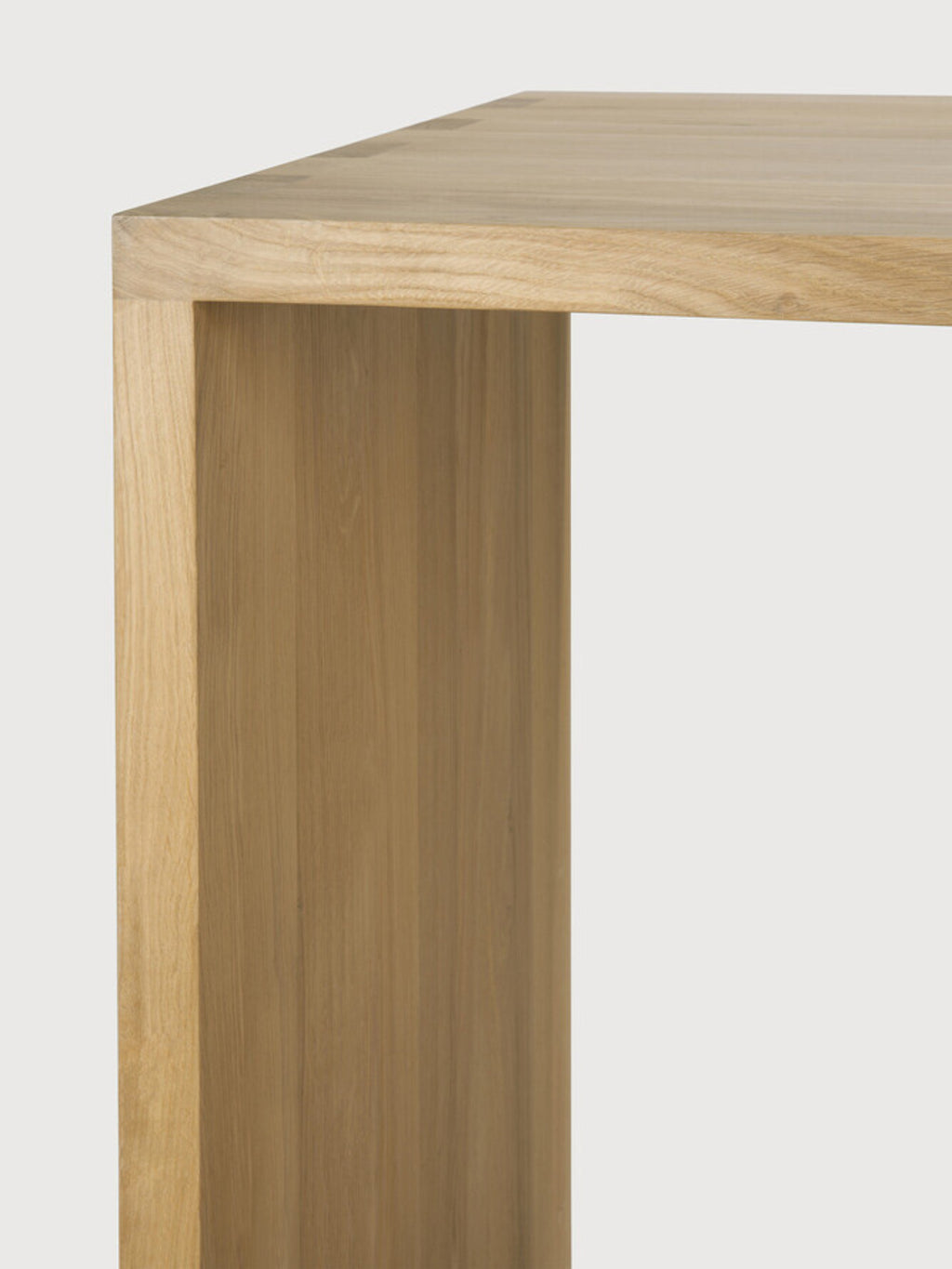 Ethnicraft U Desk, a close-up of the natural oak wood grain and sturdy, minimalist construction, showcasing the smooth, light-colored timber on a neutral background.