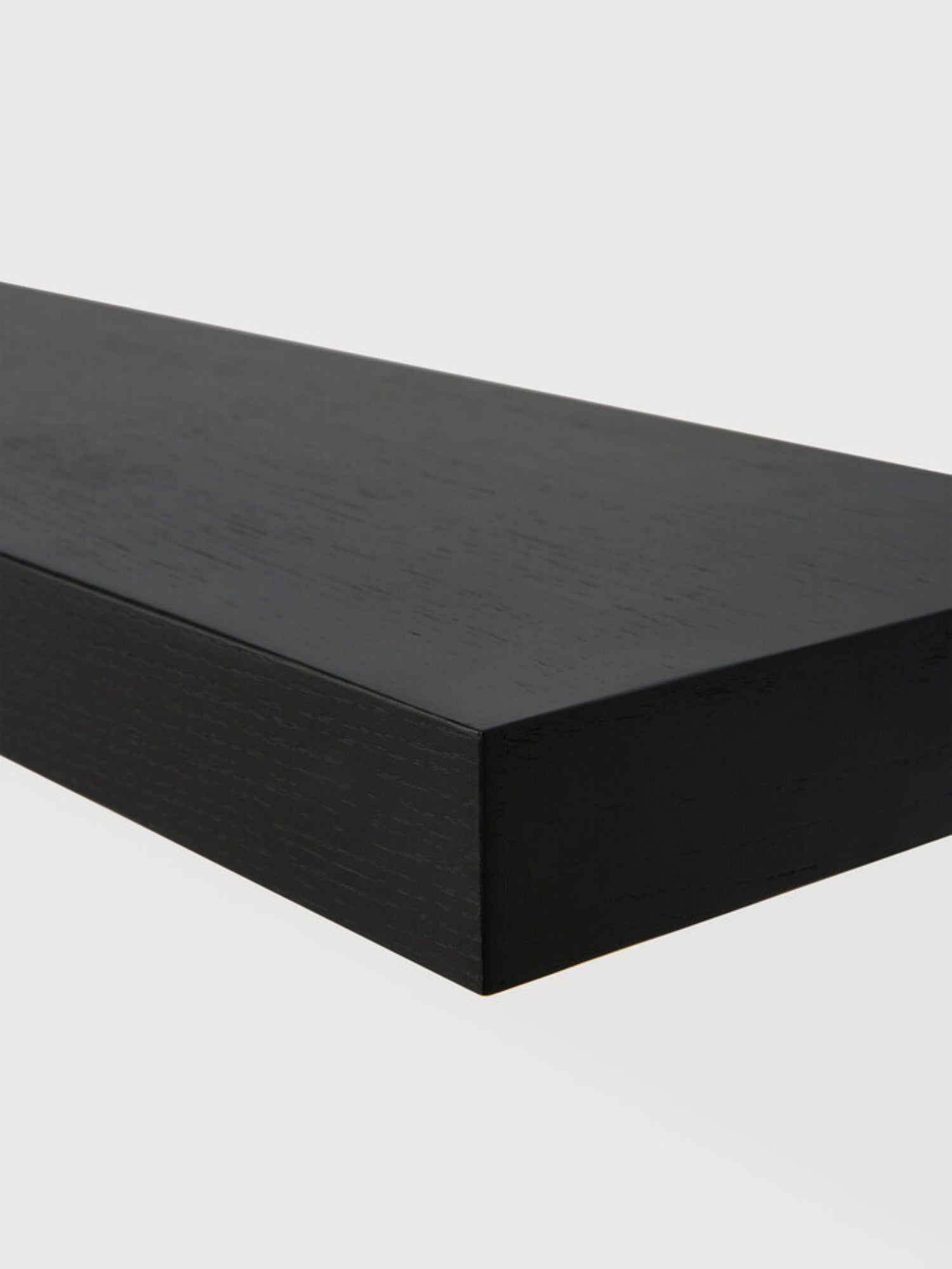 Ethnicraft Wall Shelf, a thick, rectangular matte black floating shelf crafted from solid wood with a visible subtle wood grain texture and clean, modern minimalist lines. Ideal for contemporary living rooms, bedrooms, or home offices seeking sleek display and storage solutions.