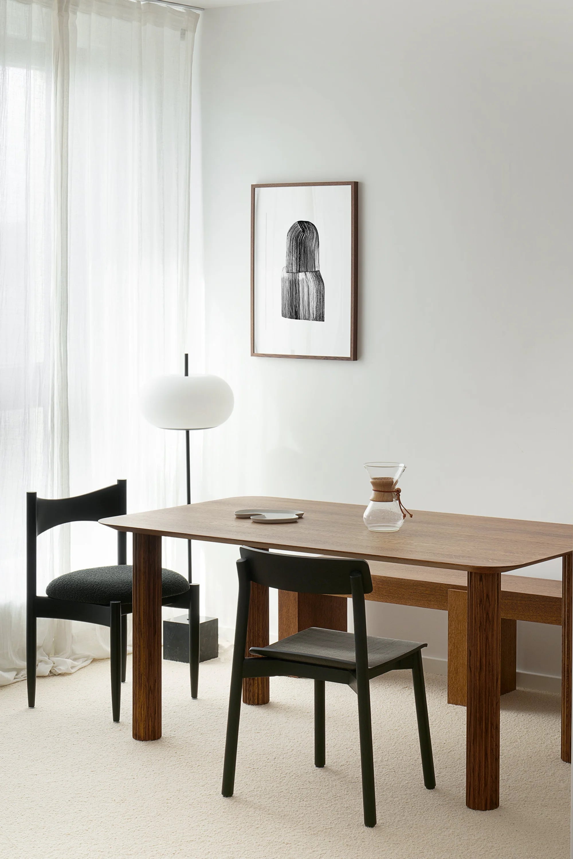 Dining room with wooden table and black chairs, framed artwork on the wall.