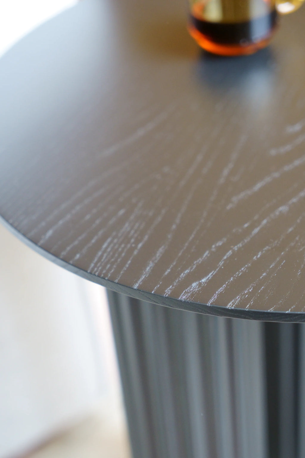 TAMO Filar Side Table, a premium modern round accent table with a dark brown top featuring distinct wood grain texture and a fluted dark grey base. Perfect for contemporary living spaces.