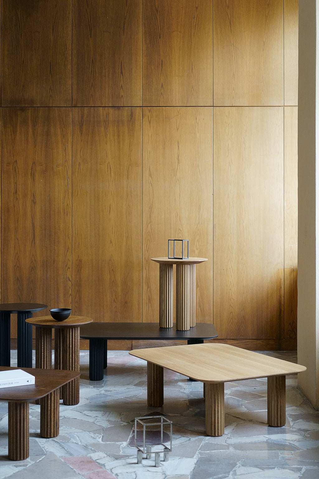 TAMO Filar Coffee Table collection in a lifestyle setting, showcasing square and round tops with fluted legs in natural light oak, dark oak veneer and black finishes on a patterned floor. These premium, versatile accent tables offer sophisticated style.