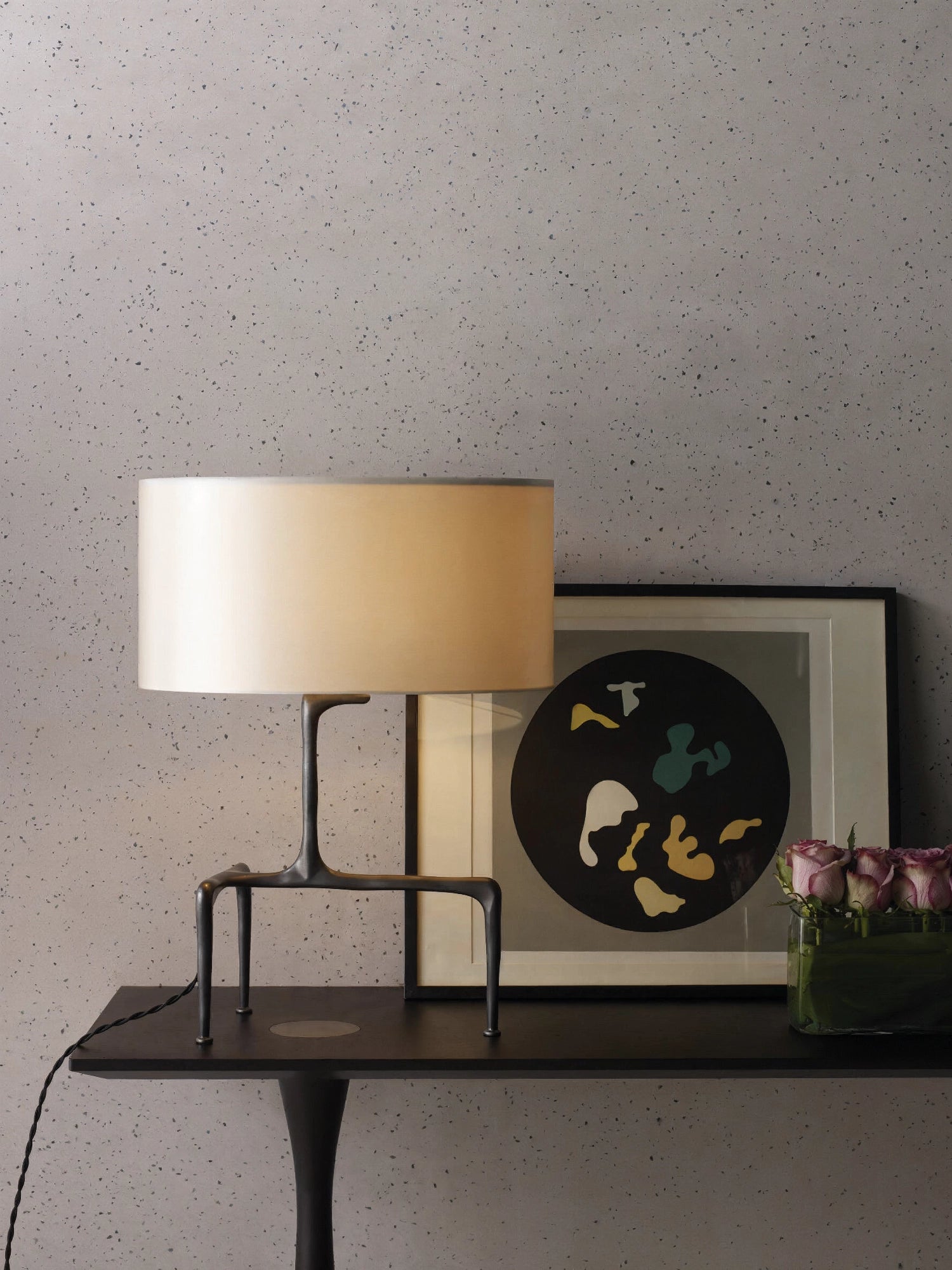 CTO Lighting Braque Table Lamp, featuring a unique, sculptural bronze base and a classic cream fabric shade, providing soft ambient light, styled on a dark console table with a modern abstract artwork and fresh roses.