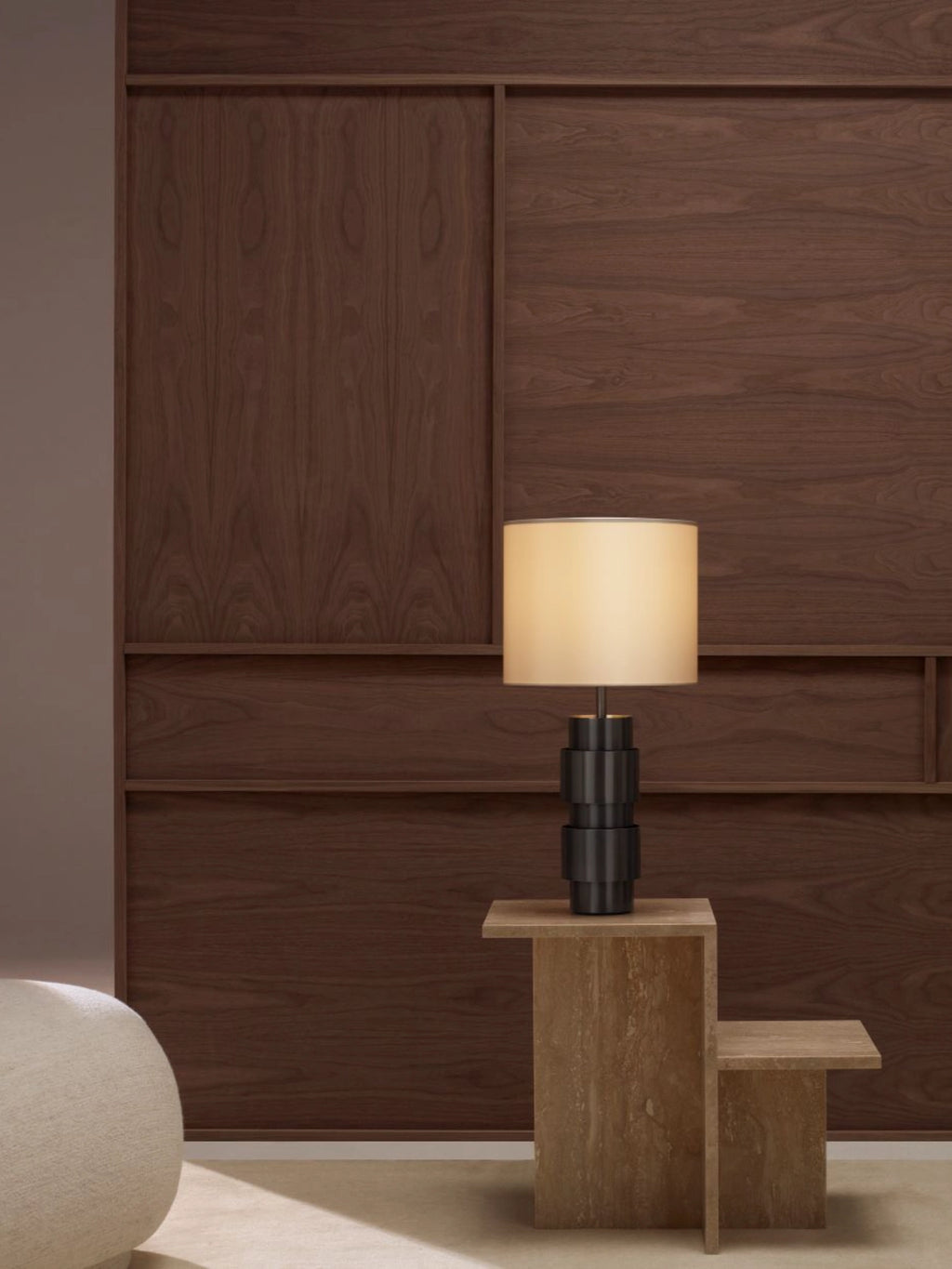 CTO Lighting Ring Table Lamp in a dark bronze finish, with a distinctive tiered base and a warm, glowing cream shade, positioned on a light wooden side table in a modern room.