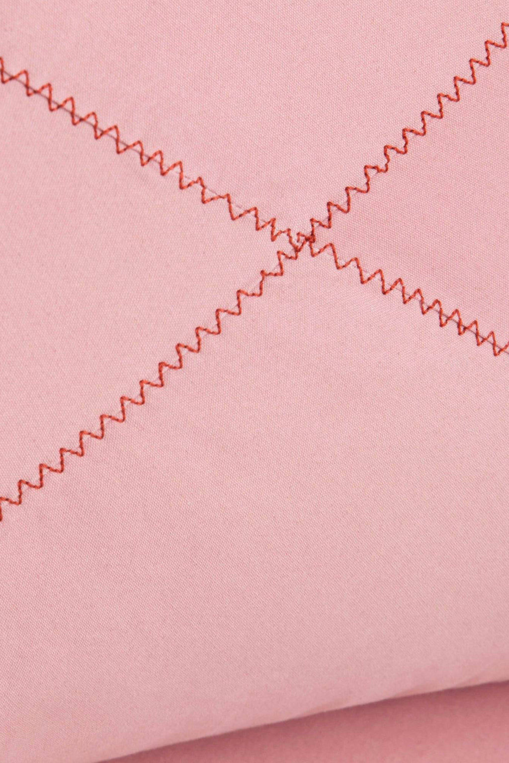 GAN Rugs Grapy Lounge Chair, showcasing a pale pink upholstered fabric with a soft, inviting texture and distinctive reddish-brown zigzag stitching that forms a subtle quilted pattern.