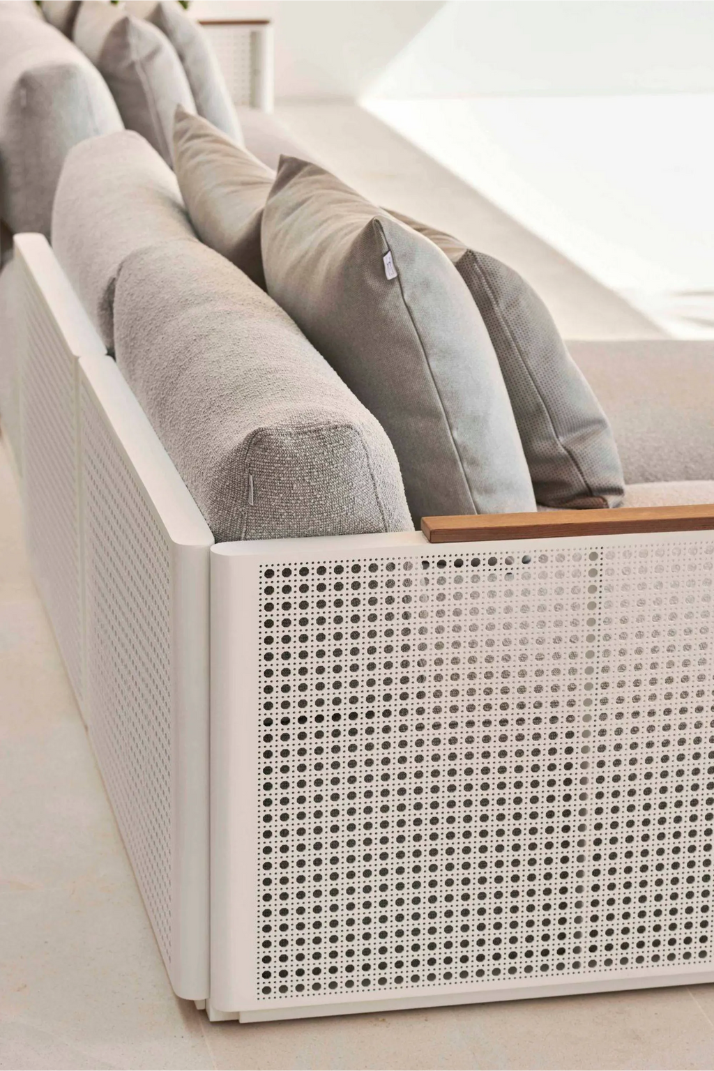 Gandia Blasco Bosc Sectional 2, a modern outdoor sofa featuring a crisp white perforated aluminum frame with a natural wood accent on the armrest, complemented by plush grey fabric cushions. This contemporary outdoor sectional offers minimalist style and comfortable seating for luxury patio and garden spaces.