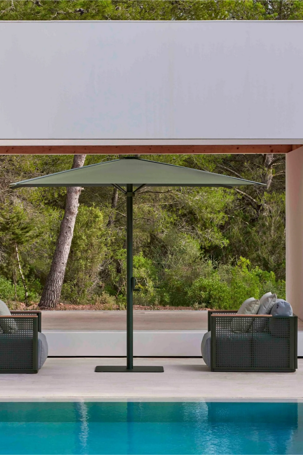 Gandia Blasco Bosc Armchair, a contemporary outdoor armchair featuring a dark green powder-coated aluminum frame with a distinctive perforated mesh pattern resembling woven cane, complemented by warm natural wood armrest tops. This modern minimalist patio seating includes plush light grey outdoor cushions, offering both style and comfort. Ideal for luxury outdoor living spaces, modern terraces, and poolside areas.