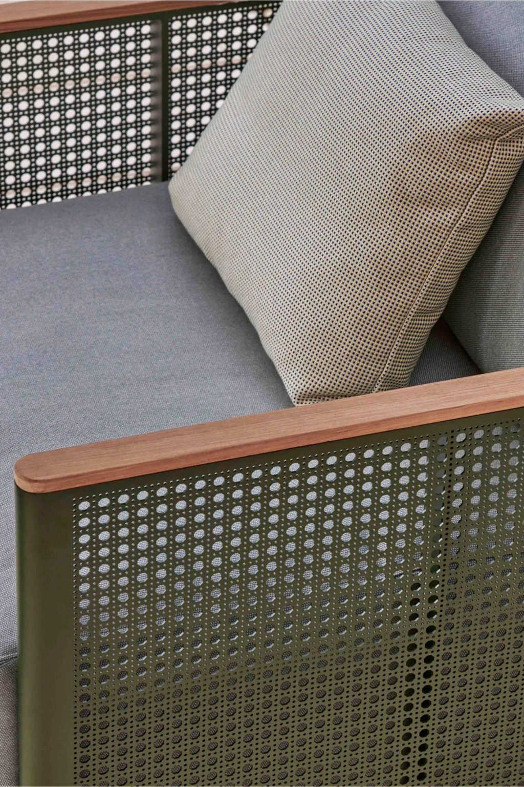 Gandia Blasco Bosc Armchair, a modern outdoor armchair featuring a distinctive matte olive green perforated metal frame with a natural wood top armrest for a contemporary design. It includes a plush grey textile seat cushion and a light grey patterned back cushion, offering comfortable outdoor seating. Ideal for minimalist patio furniture, luxury garden lounges, and modern outdoor living spaces.