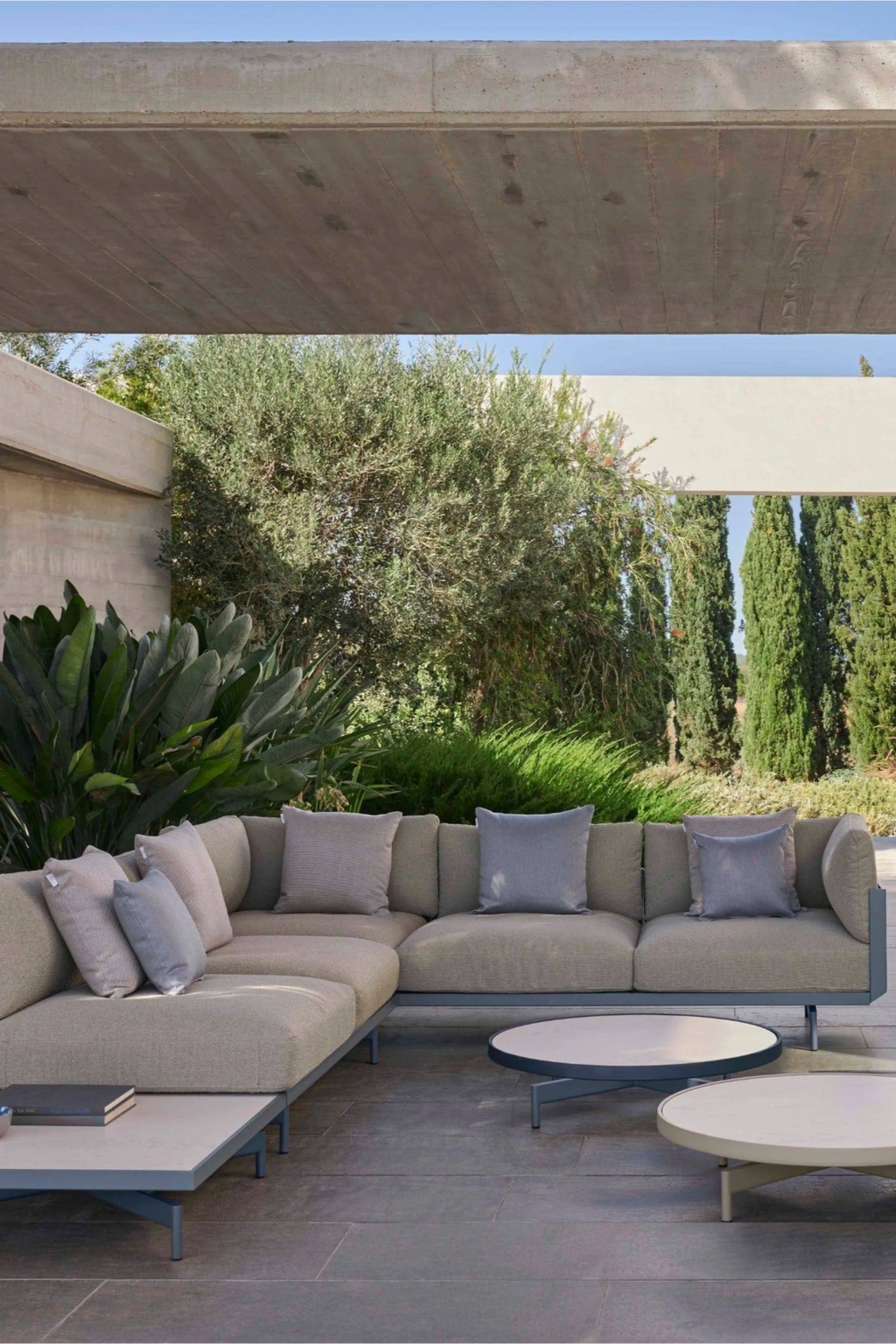 Gandia Blasco Onde 3-seater Sofa, a contemporary outdoor sectional sofa upholstered in a durable beige textured outdoor fabric with a sleek matte gray aluminum frame and gently rounded armrests. This modern minimalist outdoor lounge features plush seating and includes coordinating beige and light blue accent cushions, perfect for creating a luxurious and inviting outdoor living room or patio space.