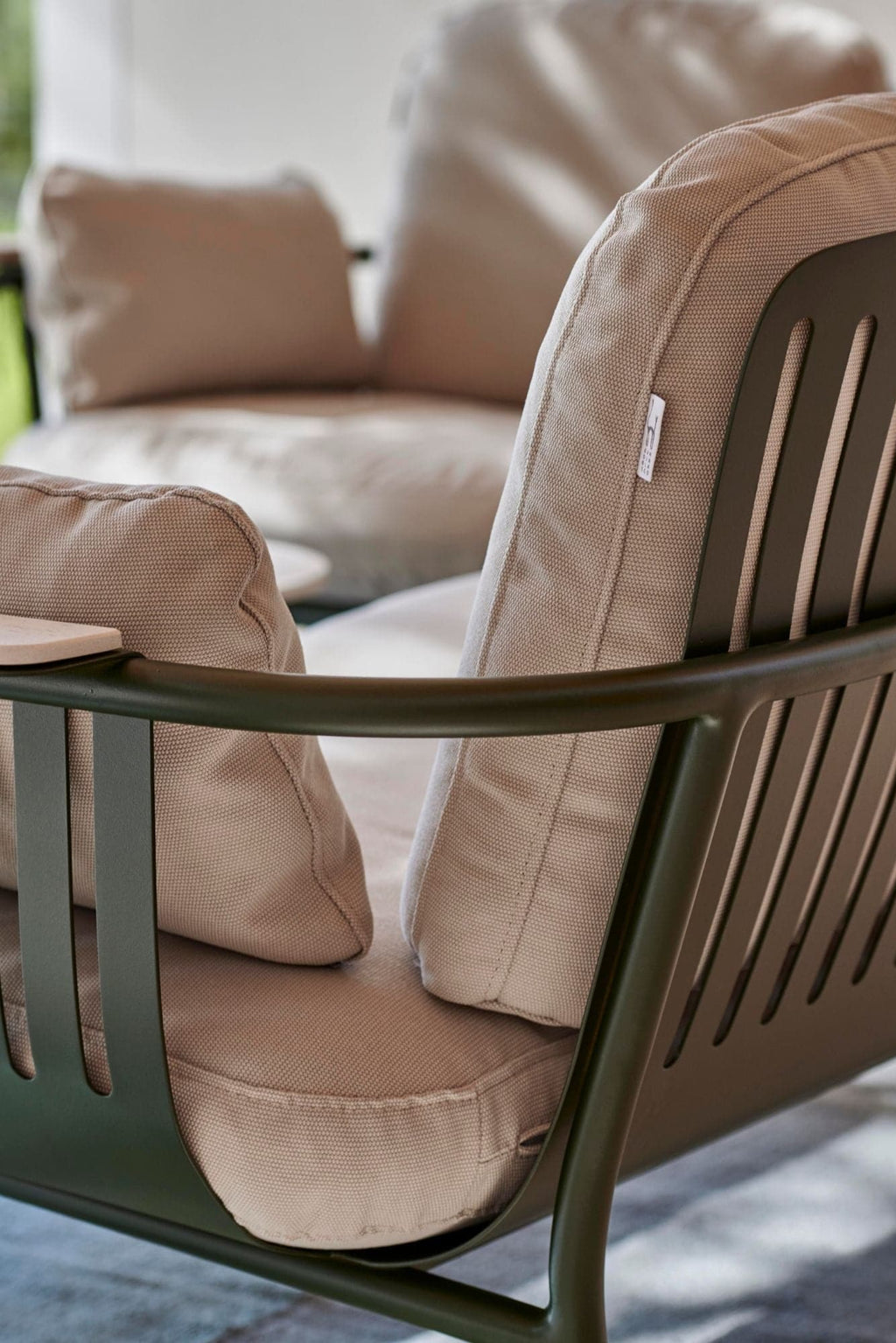 Gandia Blasco Capa 2-Seat Sofa, a modern outdoor sofa featuring a dark olive green matte metal frame with a slatted backrest and rounded armrests, paired with plush light beige textured outdoor fabric cushions. This contemporary 2-seater patio sofa is perfect for minimalist garden seating or a luxury balcony lounge.