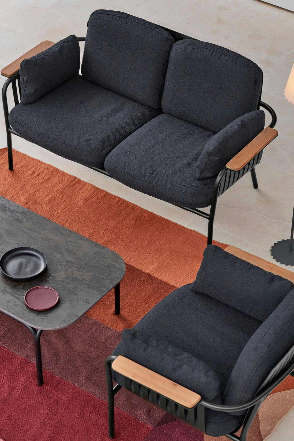 Gandia Blasco Capa 2-Seat Sofa, a modern outdoor sofa featuring a durable matte black aluminum frame with clean lines and slatted details, paired with plush charcoal grey textured fabric cushions. Its natural wood armrests add a warm accent to this contemporary patio sofa, ideal for stylish outdoor living rooms, garden lounges, or minimalist terraces.