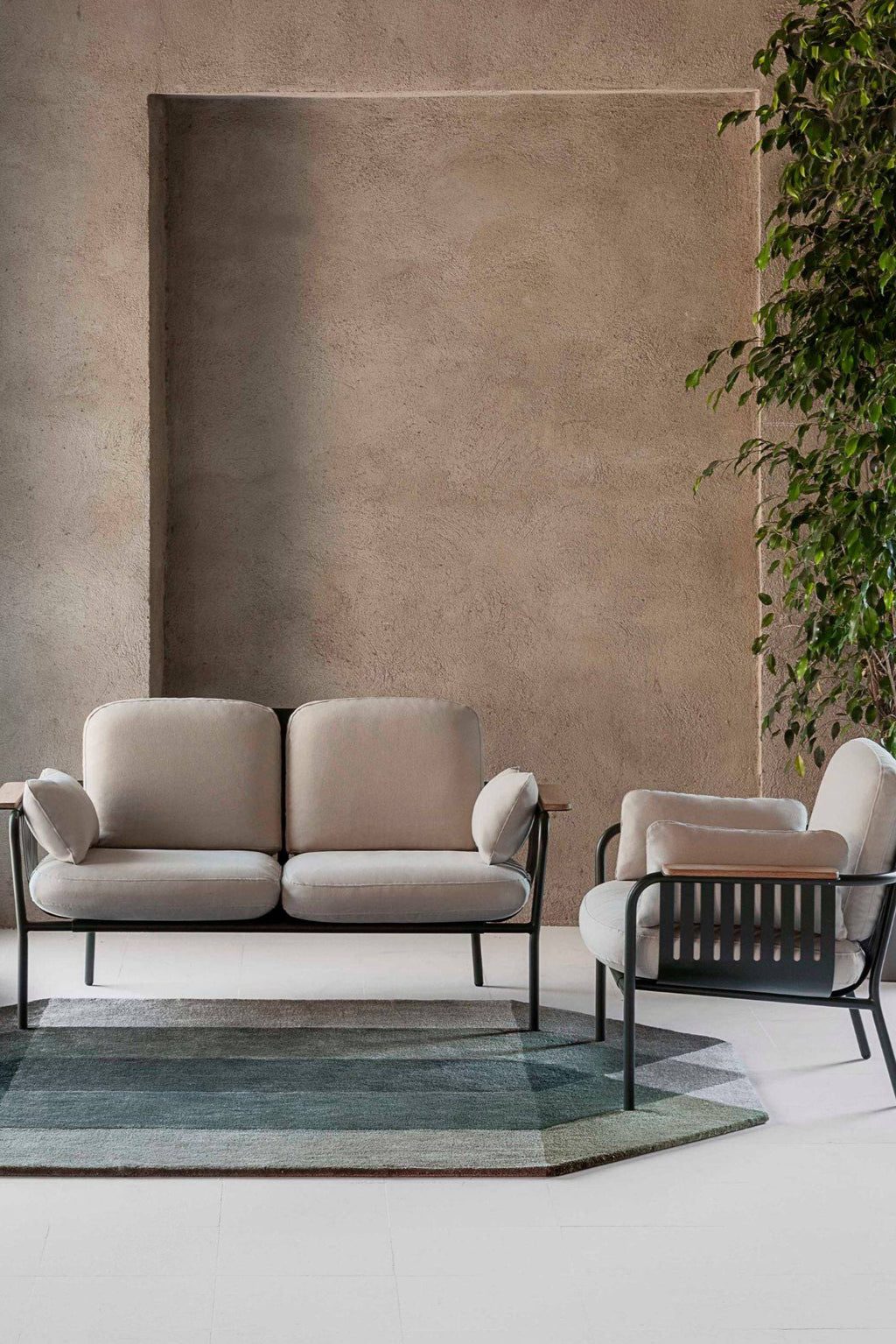 Gandia Blasco Capa 2-Seat Sofa, a modern outdoor sofa featuring a sleek matte black metal frame, plush light beige fabric cushions, and integrated natural wood armrest details. This minimalist design offers durable comfort for contemporary patio furniture, stylish garden lounge areas, or elegant outdoor living rooms.