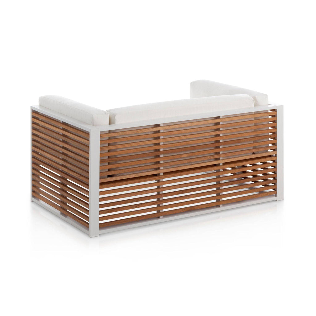 Gandia Blasco DNA Teak 2-Seat Sofa, a modern outdoor sofa featuring a crisp white aluminum frame with horizontal natural teak wood slats forming the back and sides, complemented by plush white fabric cushions. This contemporary patio furniture piece is perfect for minimalist garden lounge areas, poolside decor, or luxury outdoor living spaces.
