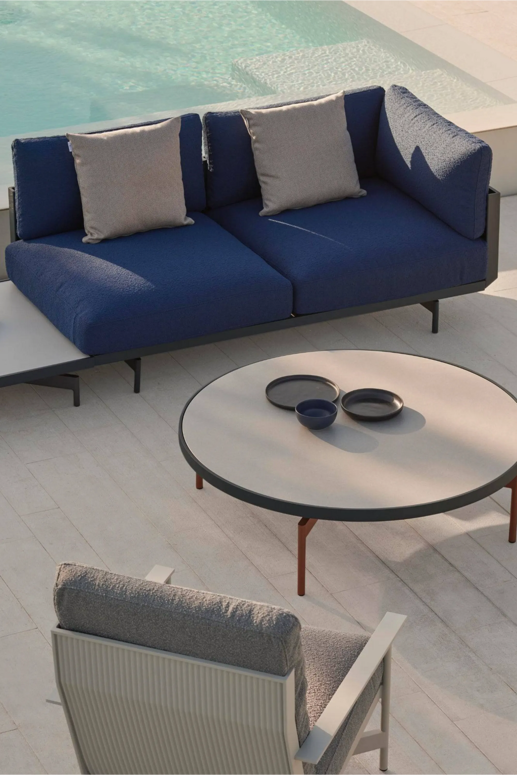 Gandia Blasco Onde Sectional 1, a modern outdoor sectional sofa upholstered in deep blue textured outdoor fabric with a sleek dark grey powder-coated aluminum frame and integrated light grey side table.