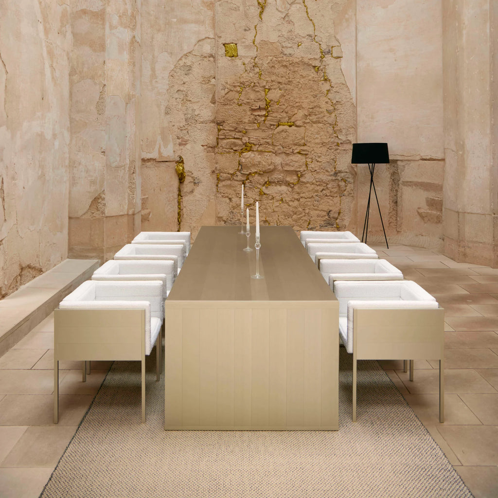 Gandia Blasco GBmodular Dining Table, a sleek rectangular modern outdoor dining table crafted from durable powder-coated aluminum in a warm light beige finish with a smooth tabletop and subtly paneled base. This minimalist outdoor dining set is complemented by matching chairs featuring clean-lined frames and plush white textured bouclé-style upholstery. Ideal for contemporary patio dining, luxury garden spaces, or modern minimalist outdoor entertaining.