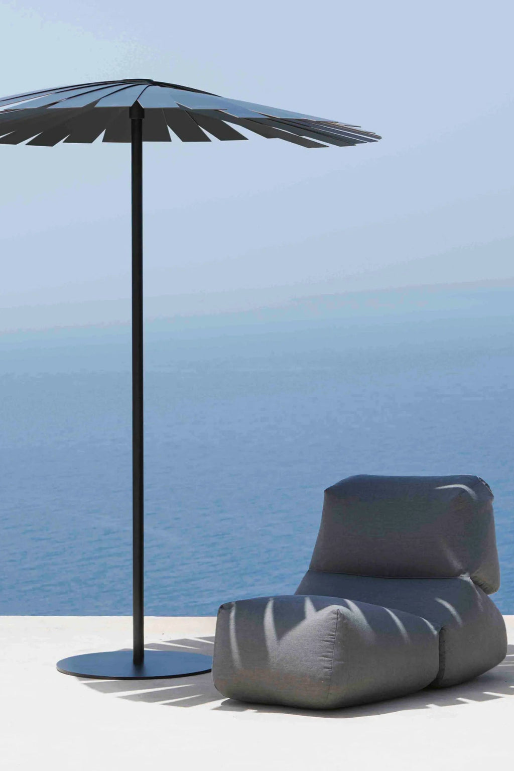 Gandia Blasco Grapy Outdoor Lounge Chair, a modern minimalist outdoor lounge chair in a deep charcoal grey durable outdoor fabric, featuring an ergonomic, plush beanbag-style silhouette designed for ultimate comfort.