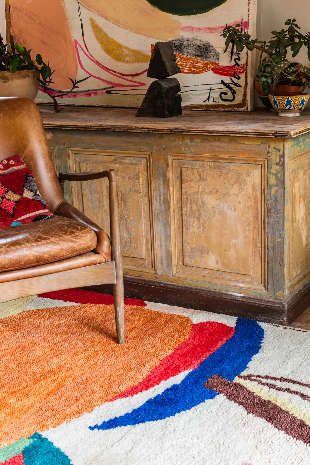 Layered Kaleidoscope Wool Rug, a vibrant modern area rug with abstract shapes in orange, red, blue, and white, featuring a plush, textured pile. Perfect for adding a bold statement to any living ro...