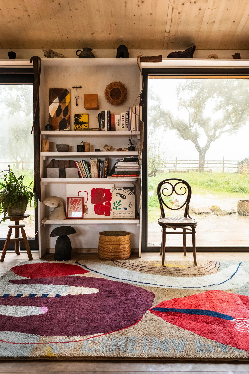 Layered Collage Wool Rug, a vibrant modern area rug featuring abstract shapes in red, burgundy, cream, and beige with blue accents. Perfect for adding a colorful, artistic touch to any living room...
