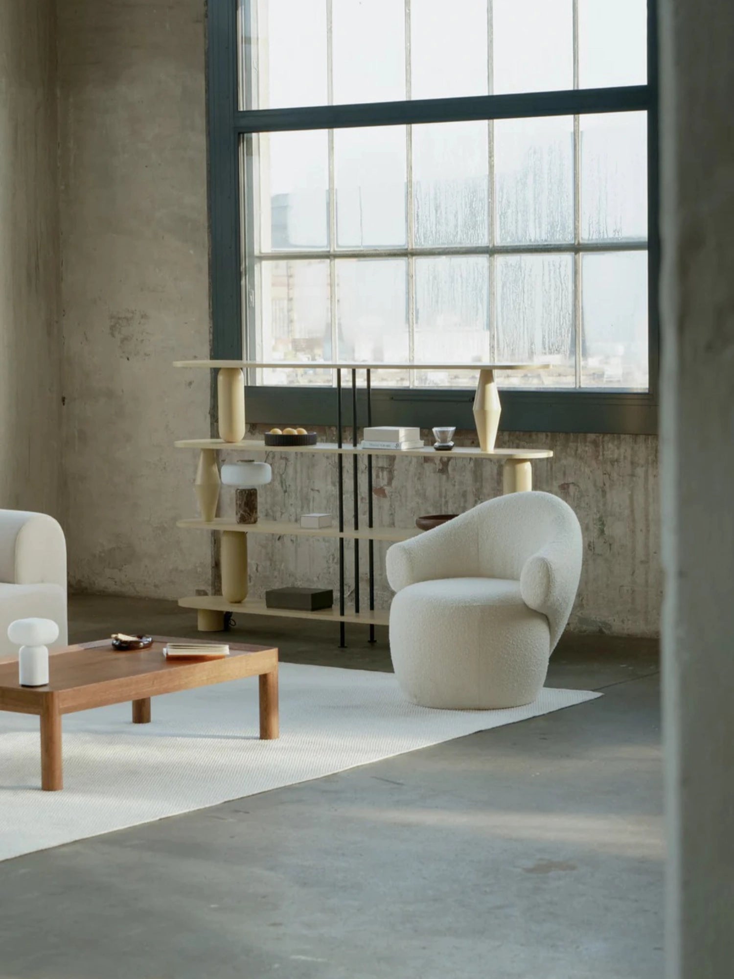 TAMO Conva Lounge Chair, a cream-colored organic modern accent chair upholstered in plush bouclé fabric, featuring a distinctive curved, sculptural silhouette and a low-slung, inviting profile. This contemporary armchair offers a soft, textured feel and sophisticated minimalist design. Perfect as a cozy living room lounge chair or a stylish bedroom accent piece.