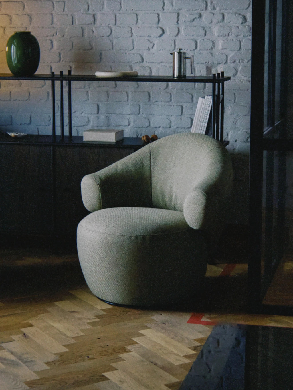 TAMO Conva Lounge Chair, a contemporary organic modern accent chair upholstered in a muted sage green textured fabric with a soft, inviting bouclé-like weave. Its distinctive sculptural silhouette features a rounded, low-profile seat, deeply curved backrest, and integrated armrests, exuding minimalist elegance. Perfect as a cozy reading nook chair or a stylish living room accent in modern and Nordic-inspired interiors.