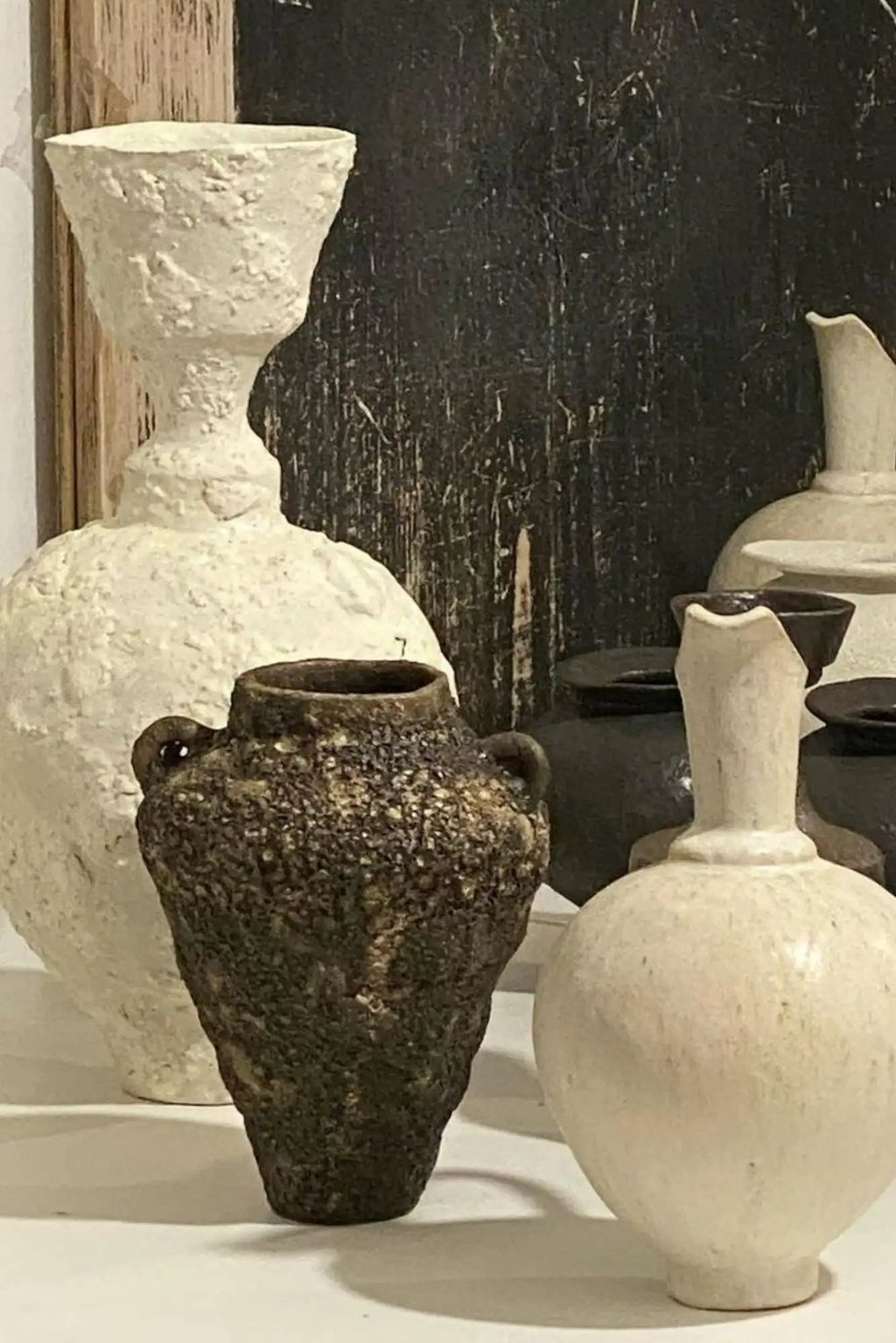 Canoa Lab Isolated n.21 Vase, a dark brown handcrafted ceramic vase featuring a deeply textured, porous, and volcanic-like finish with an artisanal, rustic appeal. This unique stoneware urn-shaped vase, complete with small loop handles, brings an organic modern touch to any space. Perfect for wabi-sabi shelf styling, a living room accent, or as a distinctive decorative object in contemporary or minimalist interiors.