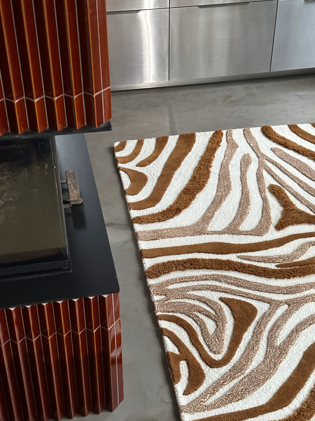 Tinted Objects Jepson Wool Rug, a stylish rectangular area rug featuring a high-low pile abstract zebra pattern in shades of white, light brown, and dark brown. This premium wool rug adds a modern, textural accent to any contemporary living space or bedroom.