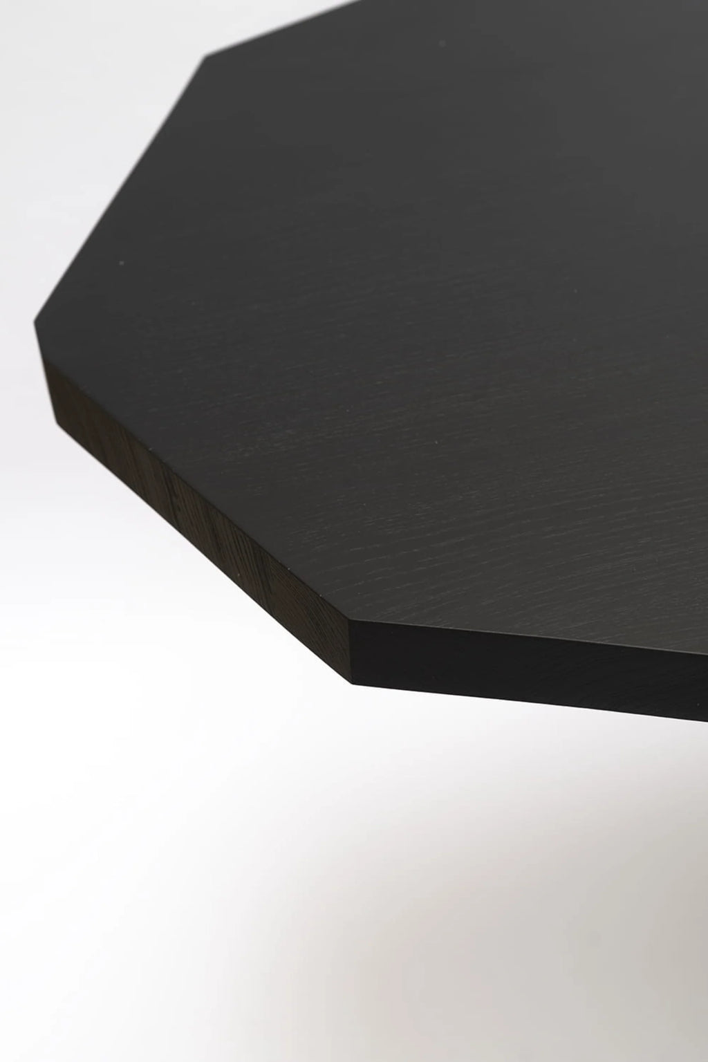 NG DESIGN Object 110 Dining Table close-up, showing an octagonal premium black wood tabletop with subtle visible grain and a thick edge. Ideal for a modern dining space.