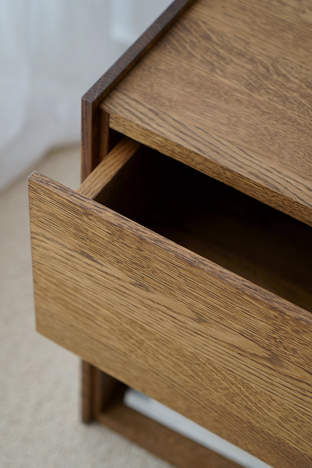 TAMO Kari Nightstand, a close-up showing the open, spacious drawer of this premium natural oak wood nightstand with subtle dark grain. Ideal for organized bedside storage.