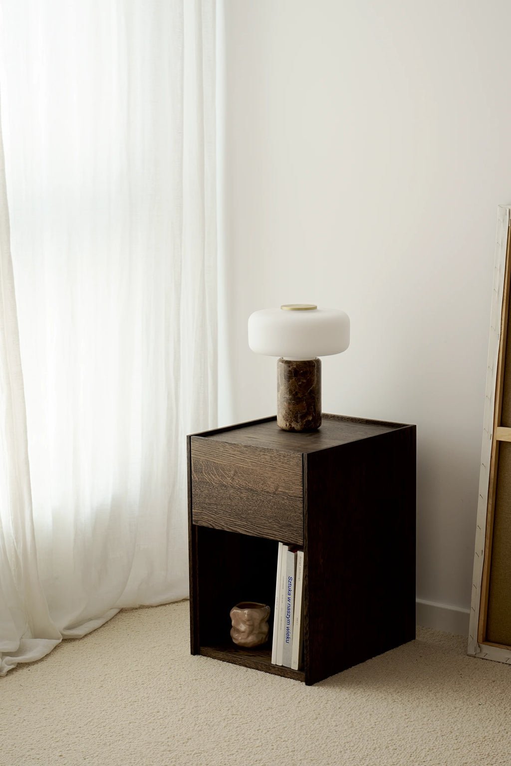 TAMO Kari Nightstand: Dark brown wooden nightstand with rectangular top, single drawer, open cubby with books & sculpture. A premium, modern furniture piece for bedroom organization.
