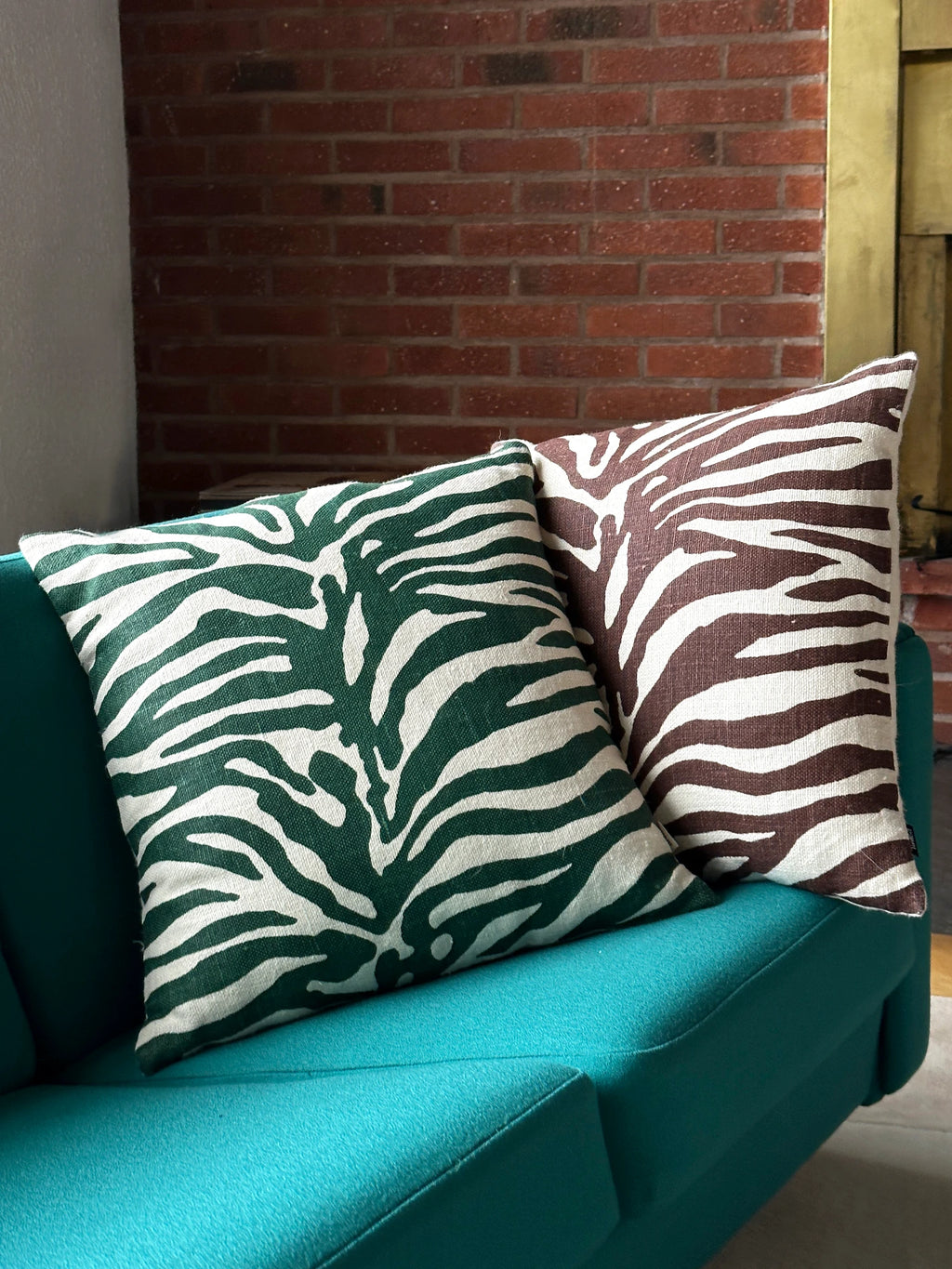 Tinted Objects Karlberg Throw Pillow, a pair of stylish square cushions with a bold zebra stripe pattern, one in deep forest green and white, the other in rich chocolate brown and white, both on a textured fabric. These decorative accent pillows are perfect for adding a touch of modern flair to a sofa or armchair for contemporary home decorators.