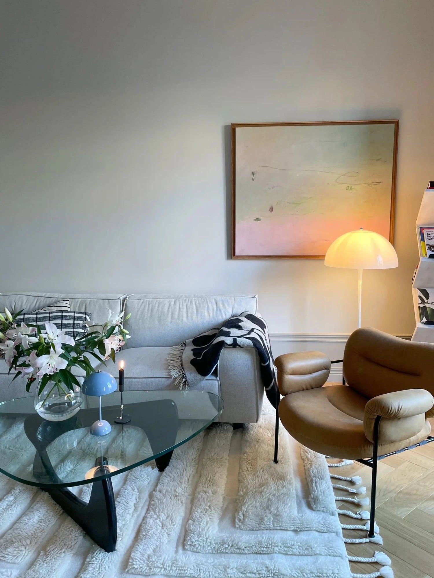 Tinted Objects Kask Wool Rug, a plush, off-white shag rug featuring varying pile heights and decorative braided tassels. This luxurious, soft rug is perfect for adding warmth and texture to a modern living room or bedroom.