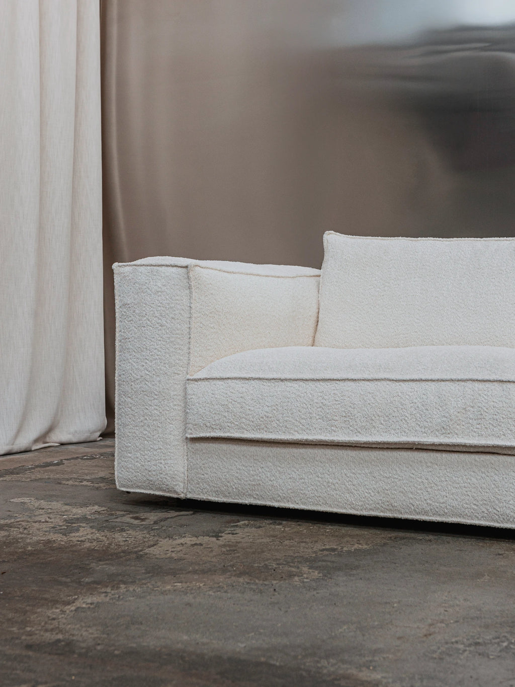 Tinted Objects Klinge Sofa, a modern off-white bouclé sofa with clean lines and plush texture, featuring subtle piping details. This stylish, comfortable sofa is perfect for contemporary living rooms seeking elegant seating.