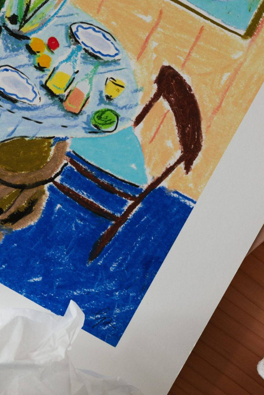 The Poster Club Pastel Table, a vibrant abstract art print featuring a dining scene rendered in expressive pastel and crayon strokes, showcasing a blue tablecloth, white plates, colorful bottles, and fruit with rich brown chair details against a warm tan and blue floor. This colorful naive style poster is perfect as modern wall art for dining rooms, kitchens, or contemporary living spaces seeking a playful touch.