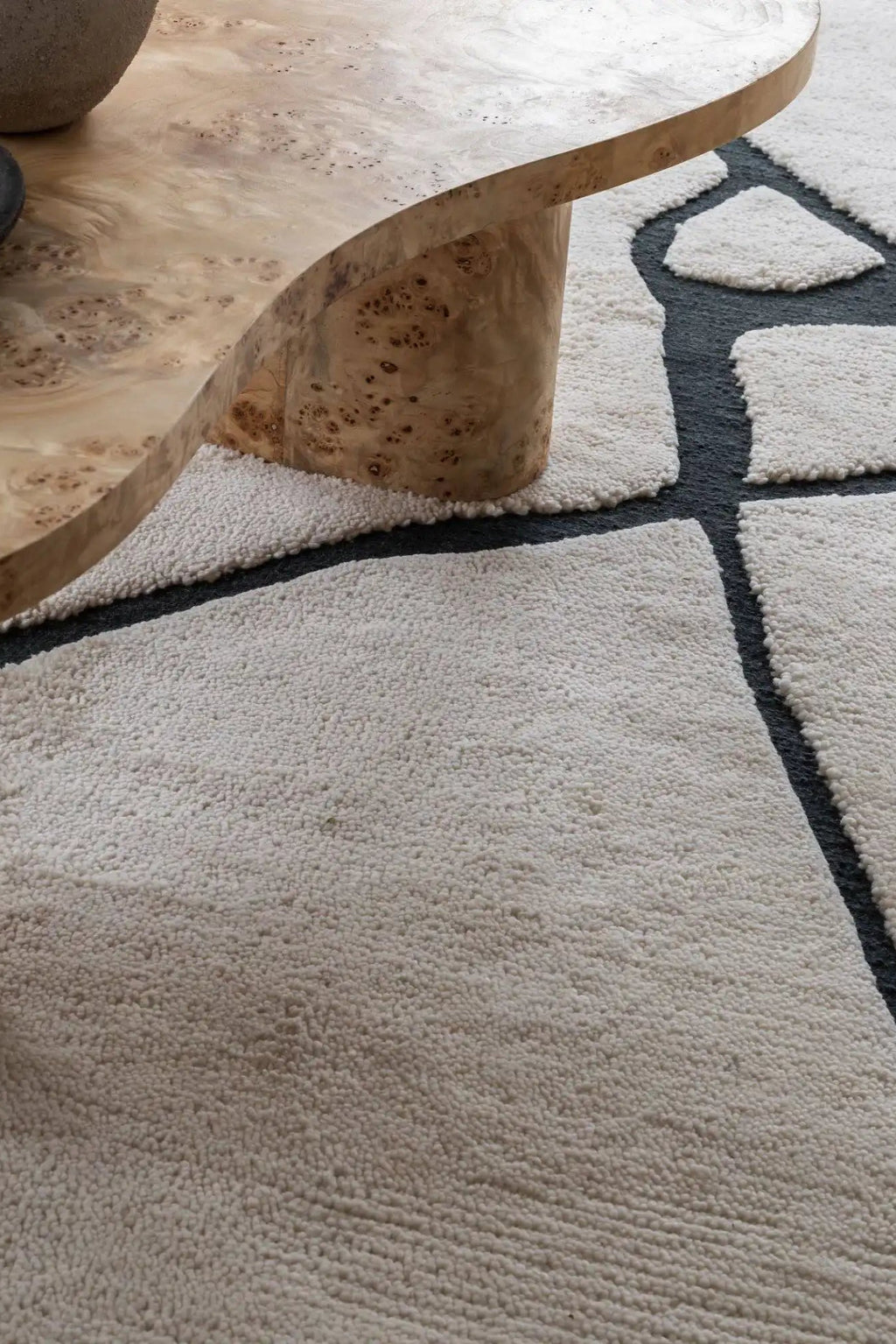 Layered Gute Wool Rug, a plush off-white textured wool rug with a modern, organic black outline pattern. Perfect for adding warmth and contemporary style to any living room or bedroom space.