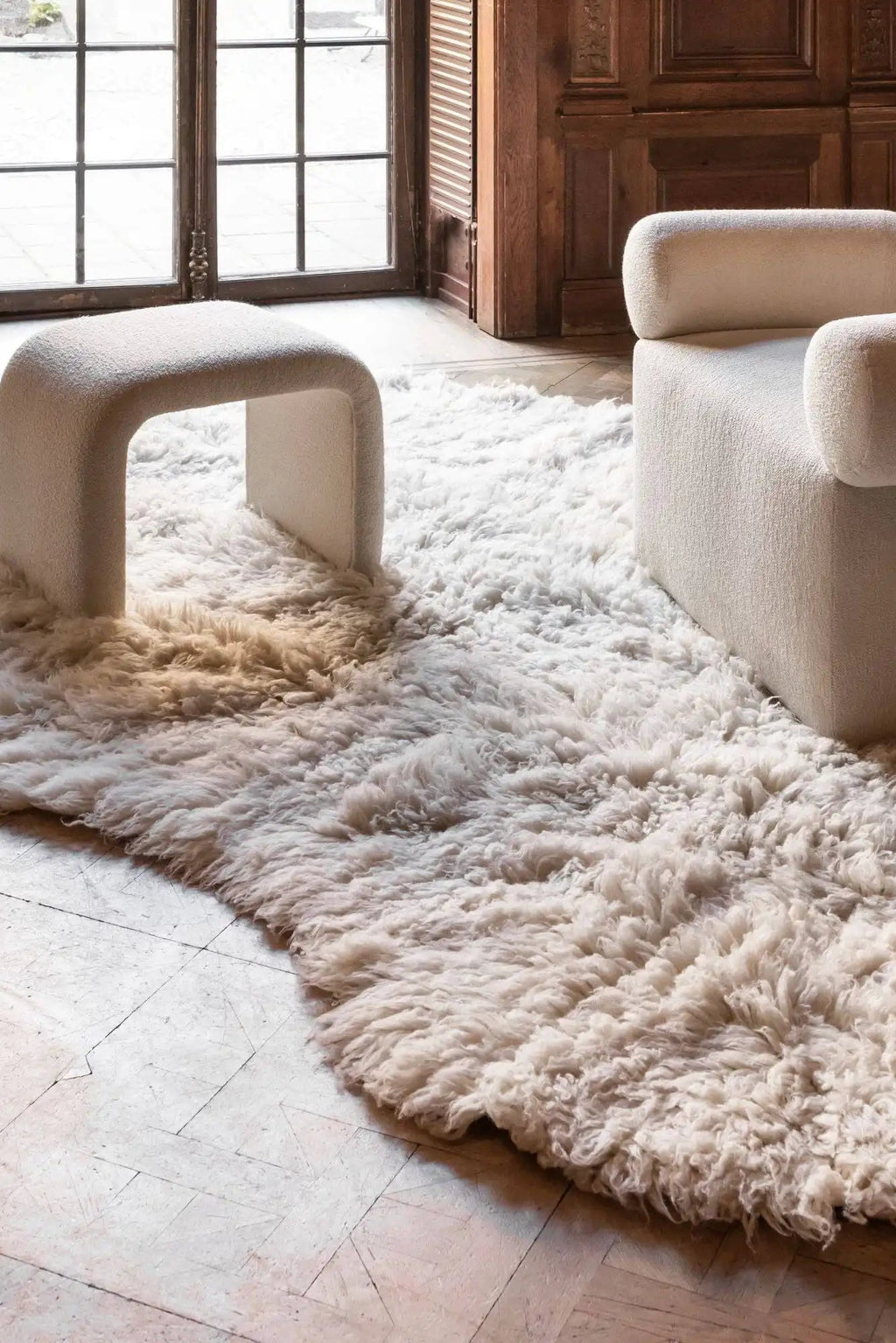 Layered Residue Shaggy Wool Rug, a plush off-white, cream-colored natural wool area rug with a thick, textured shaggy pile, partially obscuring a light wood floor. Perfect for adding cozy warmth an...