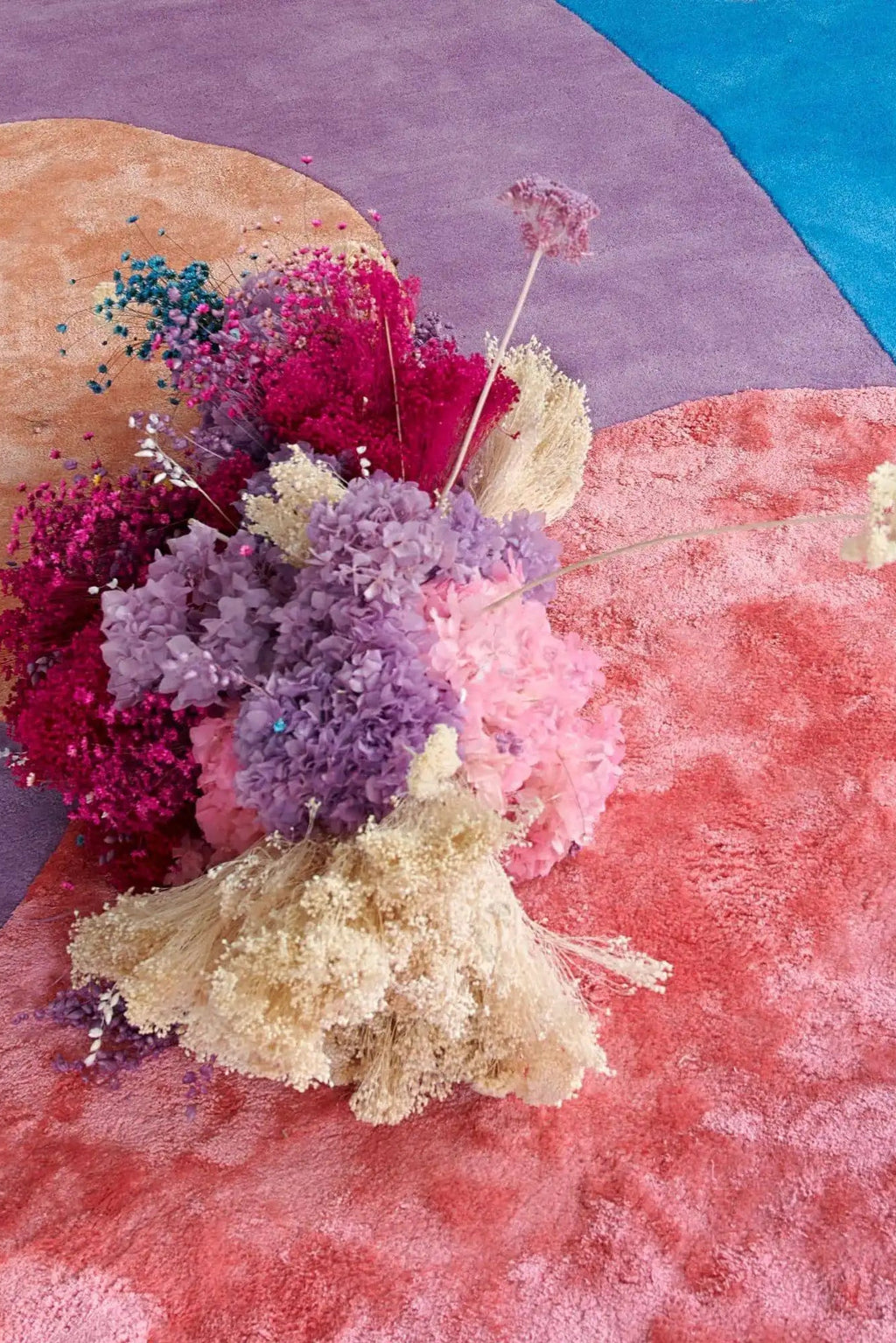 Layered Secret Garden Wool Rug, a luxurious multicolored abstract rug with soft pink, purple, and blue hues, featuring a plush, shaggy texture. Perfect for adding a vibrant, cozy touch to any livin...
