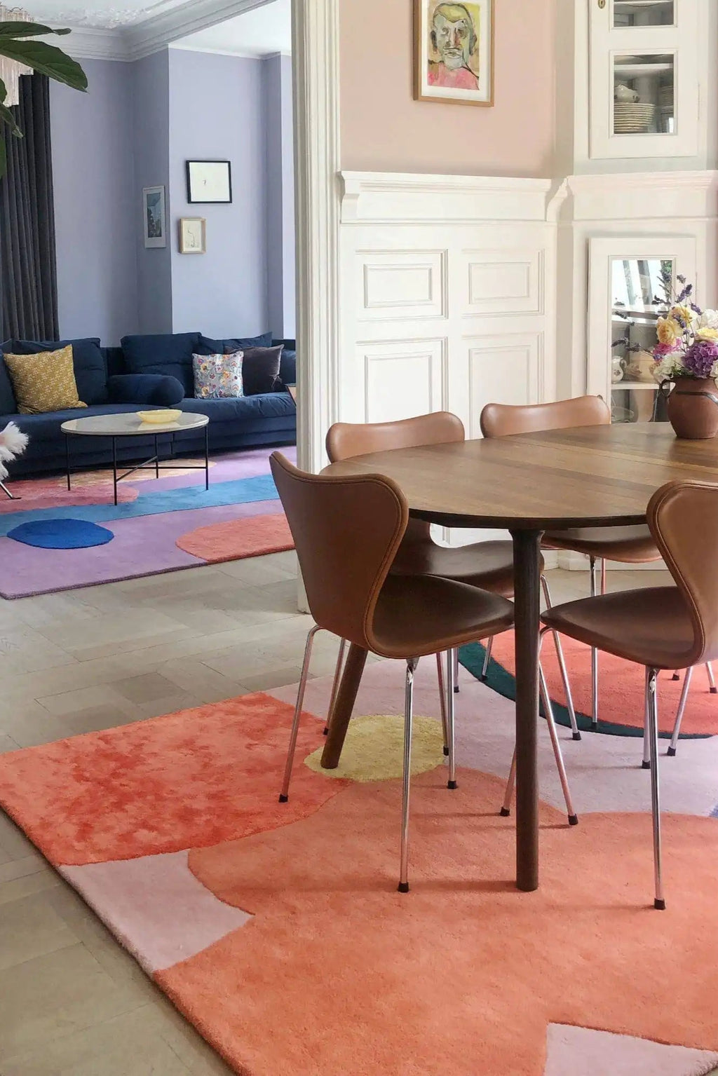 Layered Secret Garden Wool Rug, a vibrant abstract area rug featuring organic shapes in coral, lilac, blue, and yellow. Perfect for adding a modern statement piece to living rooms or dining areas.