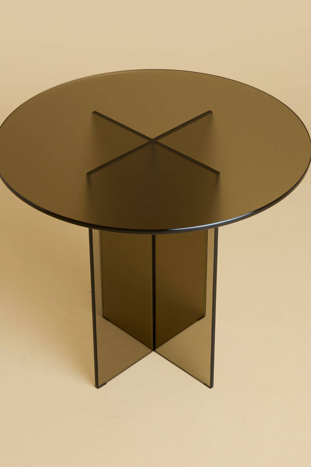 Lebanto Amami Side Table, a modern minimalist round side table crafted from dark smoked glass, featuring a sleek translucent bronze-grey finish and a distinctive geometric cross-shaped pedestal base. This contemporary glass accent table is perfect for sophisticated living rooms, bedrooms, or modern home office spaces.