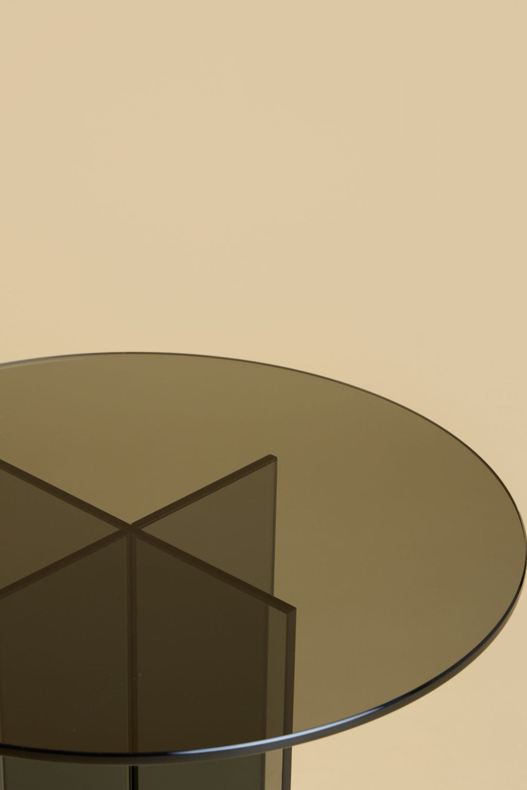 Lebanto Amami Side Table, a modern minimalist side table crafted entirely from dark smoked glass, featuring a sleek round tabletop supported by a striking geometric base of intersecting translucent panels. This contemporary glass accent table is perfect for adding sculptural interest to a living room, bedroom, or stylish lounge area.