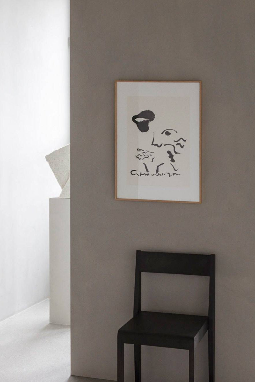 The Poster Club Sit On High, a modern minimalist abstract art print featuring bold black graphic lines and shapes forming a fragmented face against an off-white background, framed in a light natural oak frame with a crisp white mat. This contemporary black and white poster is perfect as striking wall art for a Scandinavian living room, modern bedroom, or a curated gallery wall.