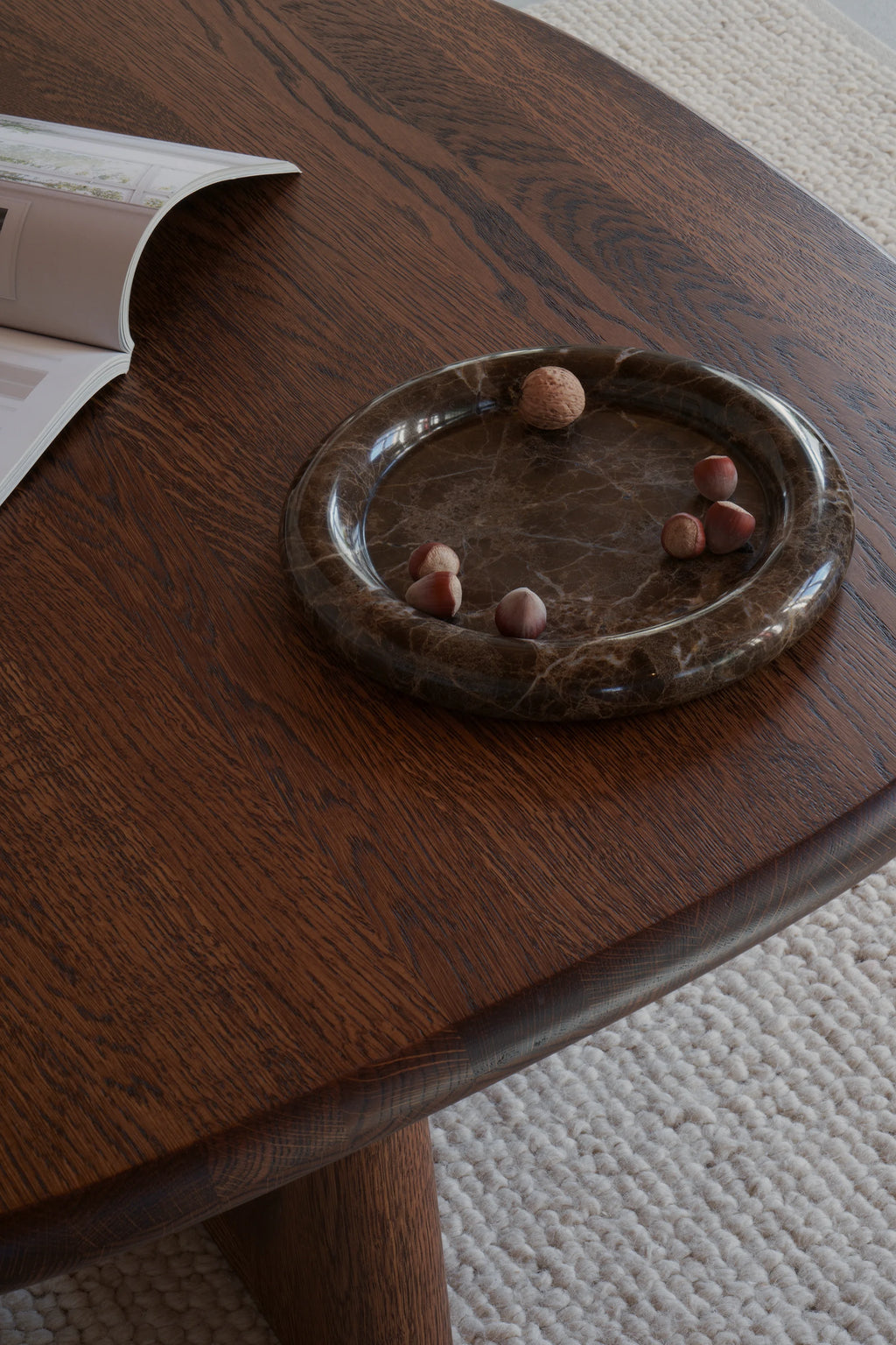 TAMO Luva Marble Tray featured on a dark wood table, showcasing its premium dark brown marble, round, low-profile design, and glossy finish. Ideal for stylish interior decor.