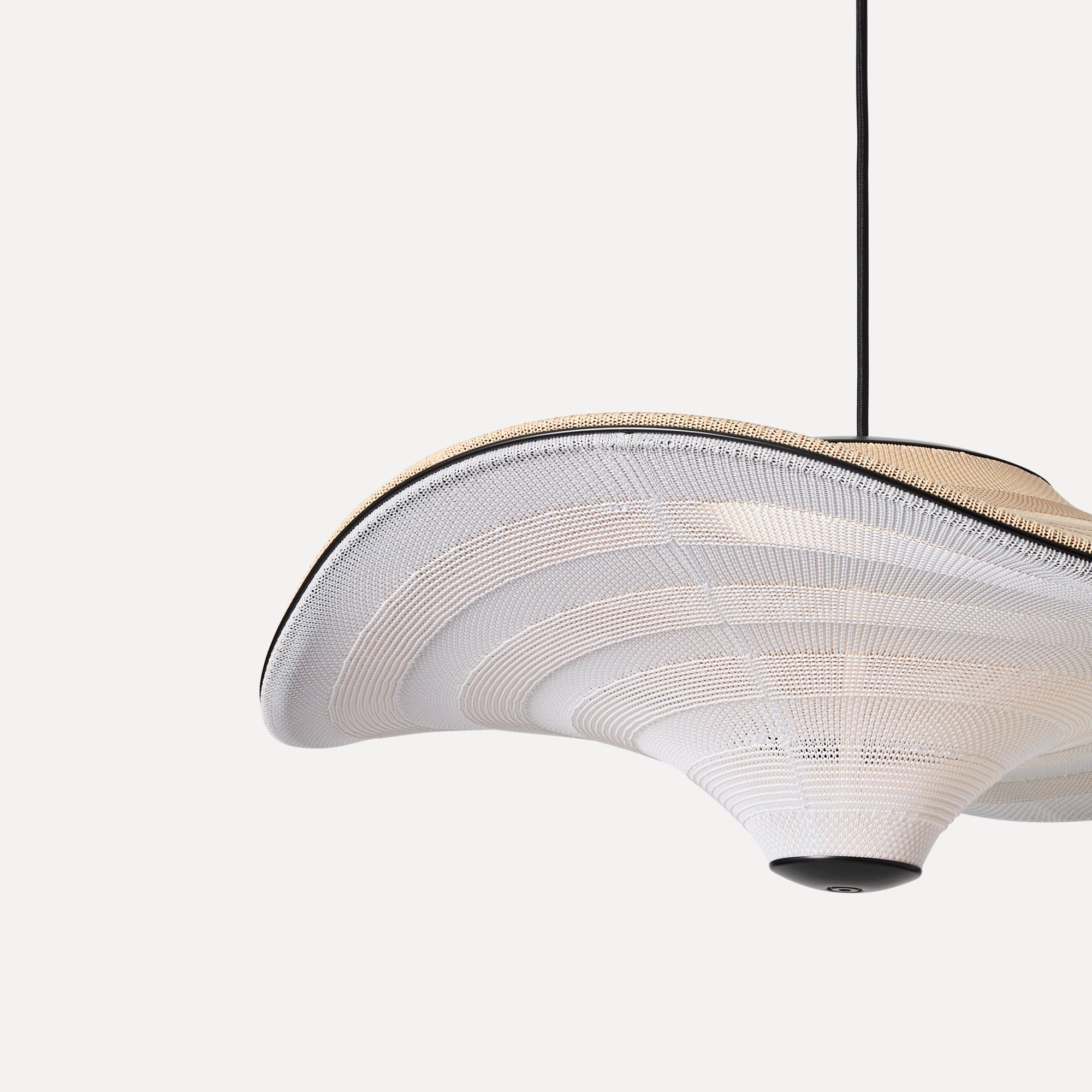 Made by Hand Flying Ø58 Pendant Lamp, an organic modern pendant light featuring a finely hand-knitted textile shade in soft cream and natural beige tones, forming an undulating, sculptural silhouette with a distinctive layered texture. This contemporary hanging lamp is detailed with a crisp matte black trim and canopy, perfect for creating ambient lighting in minimalist living rooms or Scandinavian dining spaces.