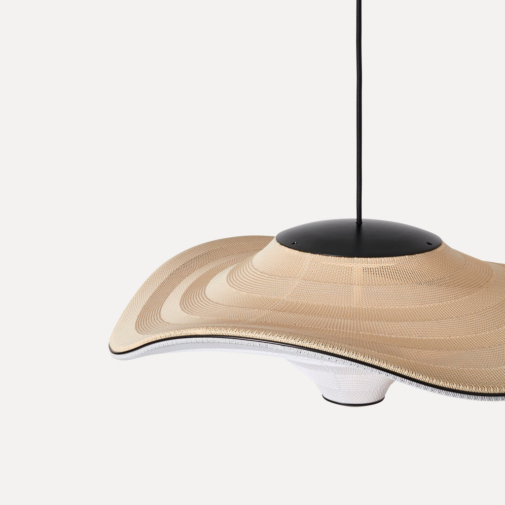 Made by Hand Flying Ø58 Pendant Lamp, an organic modern ceiling light featuring a wide, wavy, and undulating shade crafted from finely woven beige and white textile with a distinct layered texture. It is suspended by a sleek matte black metal canopy and cord, offering a contemporary minimalist aesthetic. Ideal as a statement dining room pendant light, living room accent, or for Scandinavian and Japandi-inspired interiors.