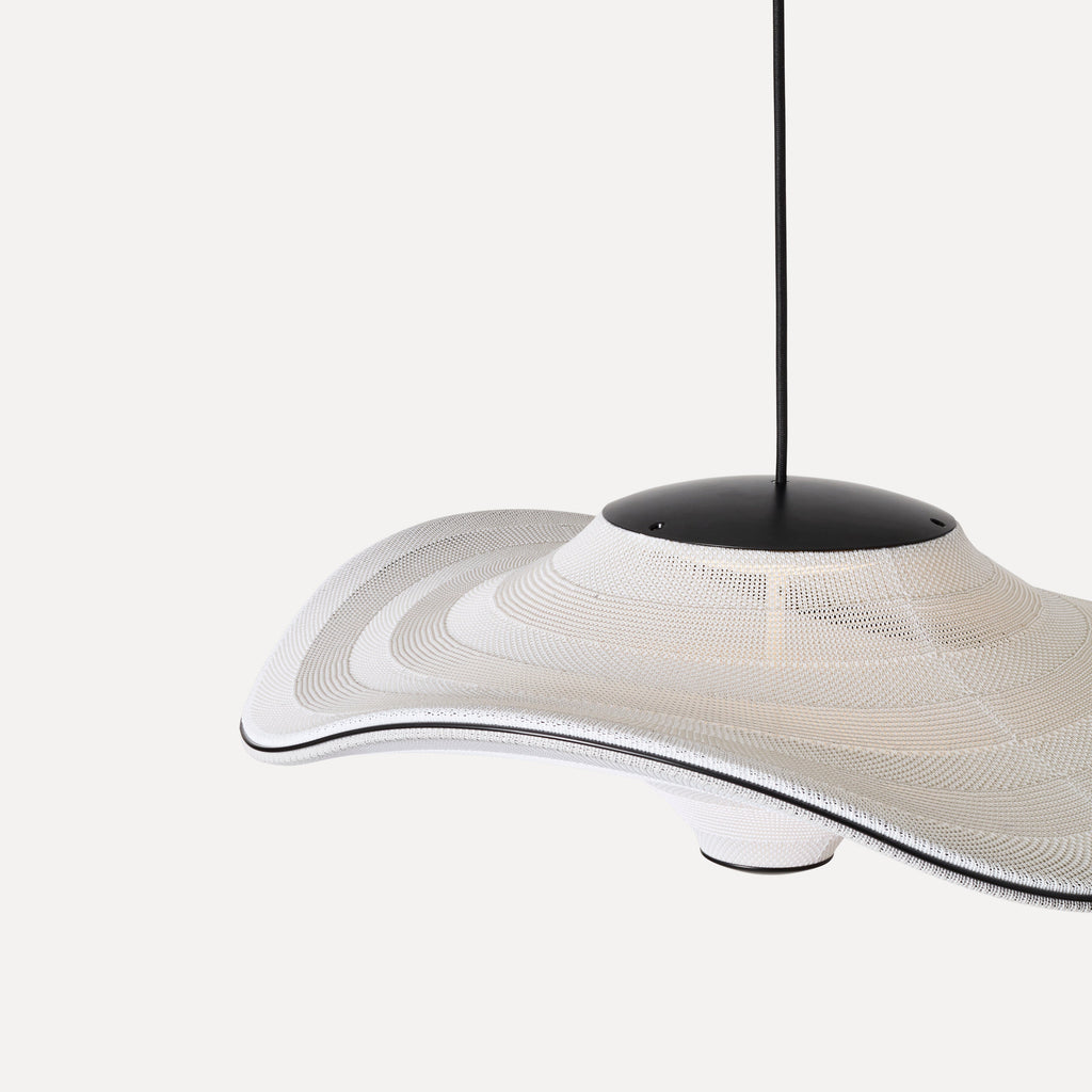 Made by Hand Flying Ø96 Pendant Lamp, a large organic modern pendant lamp featuring a wide, undulating white woven shade with a layered, perforated texture, reminiscent of a flying saucer. The sculptural shade is accented by a matte black metal canopy and a sleek black trim along its wavy edge. Ideal as a statement ceiling light for contemporary living rooms, minimalist dining areas, or spacious entryways.